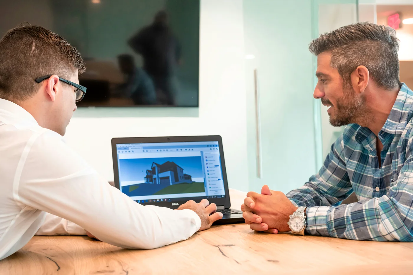 Fastighetskonsult och beställare går igenom ett byggprojekt vid en dator